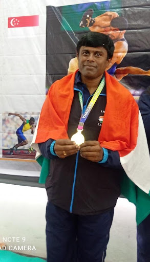 Ravi with Indian flag on his shoulders and holding his medal
