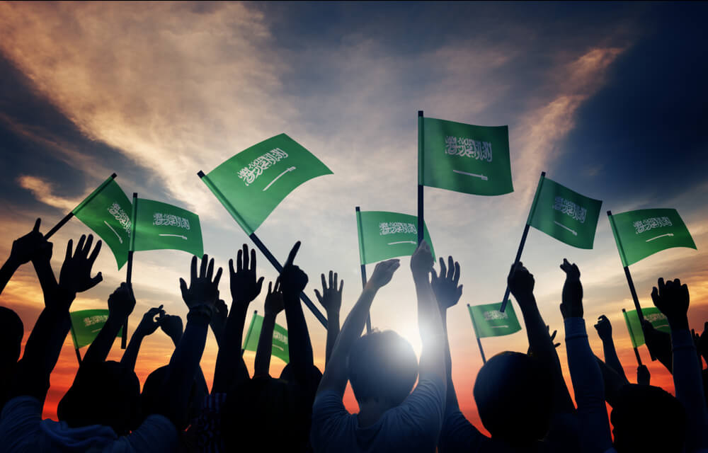 silhouettes of people holding the Saudi Arabia flag